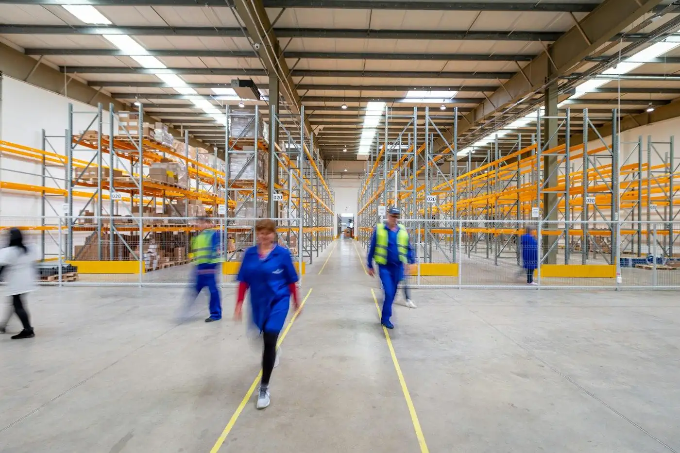 Staff walking the aisles of a large stocked warehouse