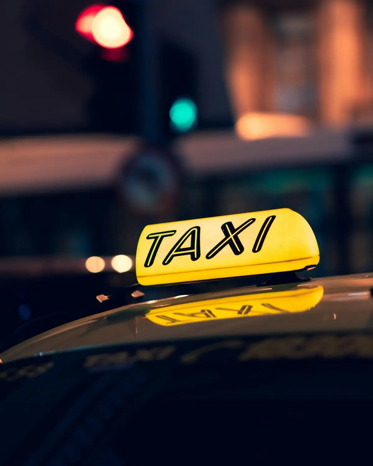 A lit taxi roof sign on a city street at night